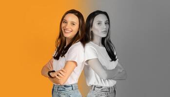 Woman positioned back to back, one exuding confidence with a joyful smile and the other showcasing a serious demeanor, against vibrant orange and gray backdrop that highlights contrasting expressions photo