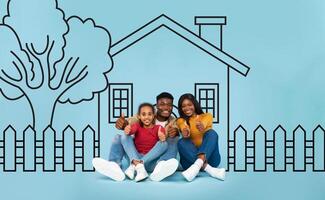 Positive black family seated on the ground in front of a house. They appear engaged in conversation or a communal activity, creating a sense of community and togetherness. photo