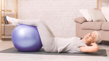 Elderly woman is engaging in a series of exercises on an exercise ball, balancing and working her core muscles. She is focused and determined, showcasing her strength and flexibility photo