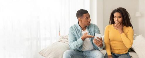 An african american couple engaging with a smartphone showing concern or confusion, with sufficient copy space for a web-banner photo