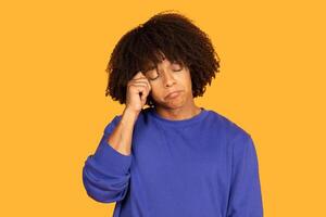 A guy appears to be expressing frustration or stress, with one hand resting on his forehead while his facial expression conveys disappointment. The backdrop is a vibrant solid yellow photo