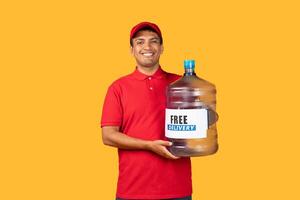 Delivery man is holding a large bottle filled with water. He has a strong grip on the bottle and is standing upright, doing delivery service, yellow background photo