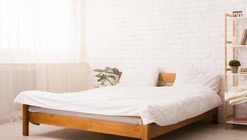 A bed is positioned next to a window in a bedroom. The room is illuminated by natural light filtering through the window. The bed is made with clean linens and pillows photo