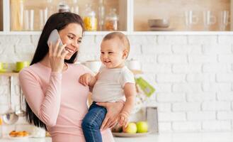 A woman holding a baby in her arms while engaging in a phone conversation. She appears focused on the call while balancing the child. Multi-tasking as a caregiver and communicator. photo