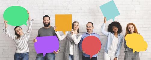 Global communications. Group of happy young diverse people holding empty colorful speech bubbles and smiling at camera photo