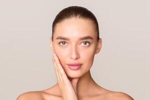 A woman is standing and posing with her hands placed on her face, creating a thoughtful or contemplative expression. She appears to be deep in thought or emotion, showcasing a moment of introspection. photo