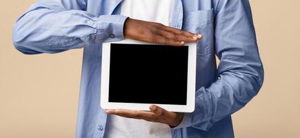 Great App. Smiling African American Man Showing Empty Tablet Screen On Yellow Background In Studio. Mockup photo