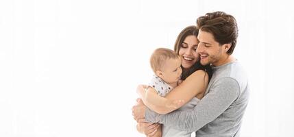 This image shows a family of three - a mother, a father, and their baby - holding each other tightly. The family is happy and smiling as they hold their little one, copy space photo