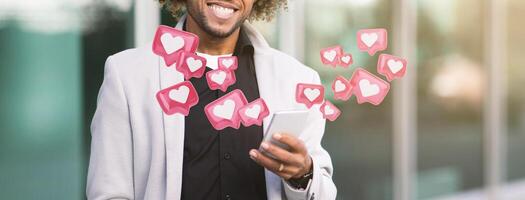 Cropped of black man with curly hair is smiling and looking at his smartphone, while multiple pink notifications with white hearts appear to be floating around him. photo