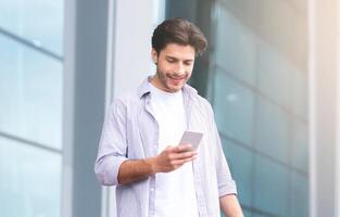 Ordering Taxi. Millennial Guy Using Smartphone While Standing With Suitcase Near Airport, Relaxing Outdoors After Flight, Free Space photo