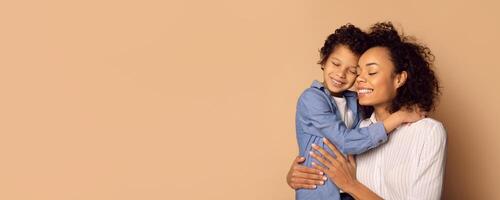 In a warm, cozy moment, African American mother holds her young child closely, both smiling with joy. The soft background emphasizes their connection and love for one another. photo