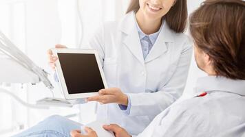 Cropped image of female dentist showing patient empty digital tablet screen, modern technologies in stomatology, copy space photo