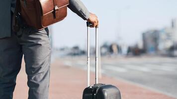 Cropped of businessman is walking with his luggage outside a modern airport. The mood is dynamic and professional, highlighting travel and business with a sleek airport backdrop. photo