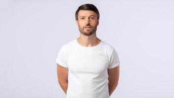 Serious Man Standing With Hands Behind His Back Looking At Camera On White Studio Background. Isolated, Free Space photo