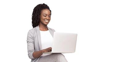 Smiling African American millennial businesswoman using a laptop, isolated on a white background, panorama with copy space photo
