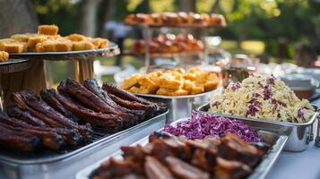 A variety of grilled meats, cornbread, and salads are displayed on a table during a summer barbecue gathering in a lush outdoor setting. photo