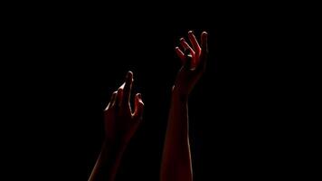 This image shows two hands reaching upwards towards the unseen, illuminated by an unknown light source. The hands are silhouetted against a dark background, cropped photo