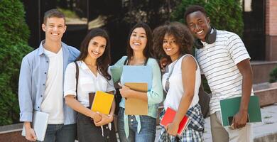 Portrait of happy international students posing outdoors near university building, smiling and embracing, taking group photo, panorama photo