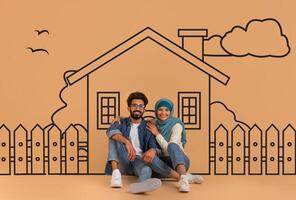 Eastern man and woman are seated in front of a detailed drawing of a house. They appear to be studying the architecture and details of the sketch together. photo