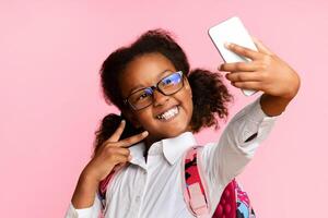 Back-To-School. Joyful Black Girl Making Selfie On Smartphone Celebrating First Day Of School Posing On Yellow Background. photo