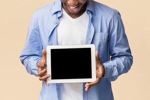 Mobile App. Afro Man Holding Digital Tablet With Blank Screen Standing Over Yellow Studio Background. Mockup photo