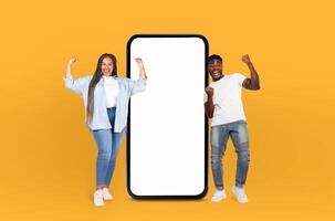 Black couple standing side by side in front of a blank screen placed on a vivid yellow background. They appear to be engaged in some form of interaction or presentation. photo