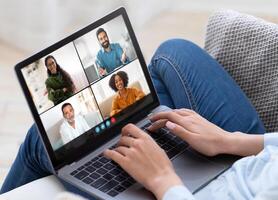 Colleagues participate in a virtual meeting from the comfort of their homes, engaged in discussion and presentations through a laptop using videoconferencing software. photo