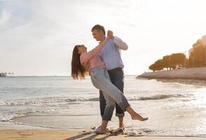 A couple enjoys a romantic dance on the beach, holding hands as the sun sets. The waves gently lap at their feet, creating a serene atmosphere filled with love and joy. photo