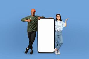 Two multiracial people standing in front of a blank screen on a blue background. They are striking poses and seem to be engaged in a photoshoot or presentation. photo