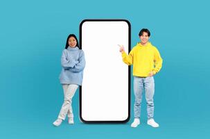 Chinese man and woman standing side by side next to a large telephone. The man is wearing a blue shirt and jeans, while the woman is in a white dress. Both are looking at the phone. photo