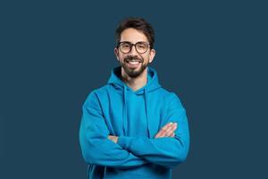 un hombre vistiendo un azul capucha soportes con su brazos cruzado, mirando Derecho adelante. su cuerpo idioma sugiere un sentido de determinación y confianza. foto