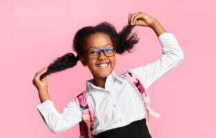 Joyful Black Schoolgirl Playing With Ponytails Happy About Upcoming Back To School Posing On Yellow Background. Studio Shot photo