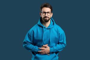 Photo portrait of man grimacing touching stomach injury poisoning disbalance diarrhea isolated on bright blue color background