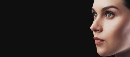 A close-up shot of a womans profile against a dark background. She is looking off to the side with a serious expression. photo