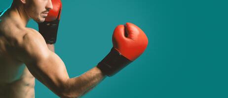 A man wearing boxing gloves strikes a strong and confident pose against a vibrant blue background. His muscles are tense, and he exudes a sense of power and determination, copy space photo