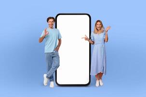 European couple smiles are infectious as they stand side by side, presenting a large smartphone with a pristine, empty screen, ready to capture the imagination. photo