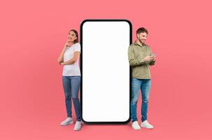 A man and a woman are depicted standing next to a large phone in this scene. They appear to be looking at the phone, possibly engaged in a conversation or using its features photo
