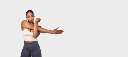 African American woman in the image is flexing her arm, showcasing her muscle definition. The background is plain white, emphasizing the focus on her flexed arm, panorama, copy space photo