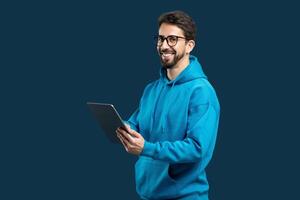 un hombre vistiendo un azul capucha es participación un tableta dispositivo en su manos. él aparece enfocado en el pantalla, posiblemente desplazamiento o interactuando con el tableta. foto