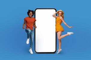 Two individuals are energetically jumping in front of a blank screen against a blue background. The action captures a moment of dynamic movement and excitement as they leap into the air. photo