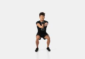 A man is engaged in a squat exercise while holding a dumbbell in each hand. This athletic endeavor takes place in a sleek indoor gym setting with bright ambient lighting photo