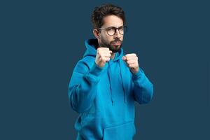 A man wearing a blue hoodie is shown with his fist raised in the air, showcasing a gesture of determination or protest. The background is nondescript, highlighting the mans action. photo