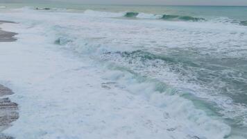 Aerial view capturing wind waves crashing fluidly on a freezing ocean beach video