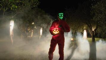Man With Anonymous Mask Walks At Night With Halloween Pumpkin In Foggy Forest video