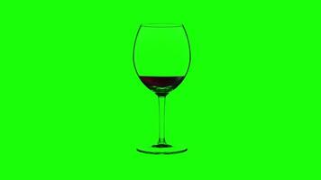 Empty wineglass filling up with red wine on green background video