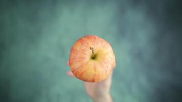 Hand throws up and catches red apple above table surface video