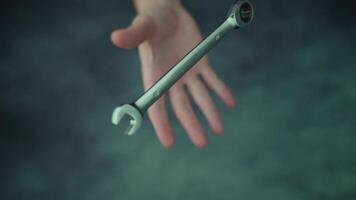 Throwing up and catching wrench over blurred table surface video