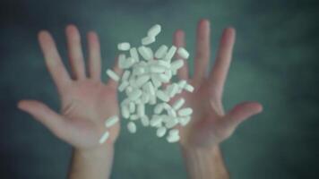 Both hands throwing up handful of pills above table surface video
