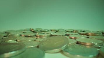 Coins fall down onto pile on white background at green light video