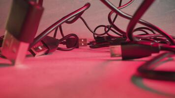 Knotty USB wires at red illumination of studio room macro video